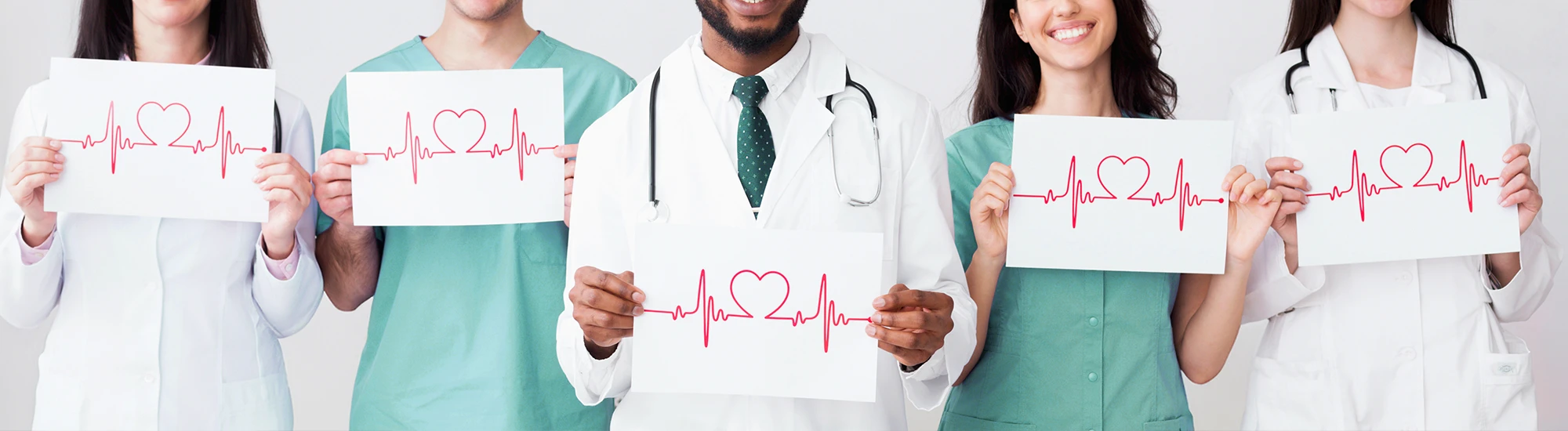 Ärzte-Team hält Zeichnungen von Herz und EKG-Linie